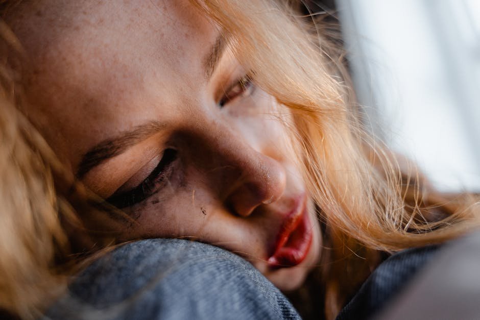 A close-up of a young woman resting her head, appearing thoughtful and introspective.