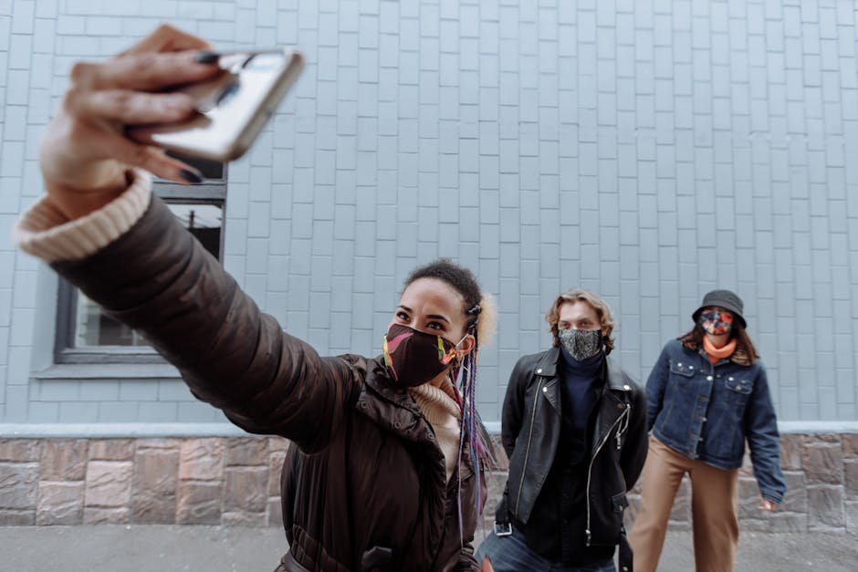 Three friends wearing face masks take a selfie outdoors, highlighting pandemic life.