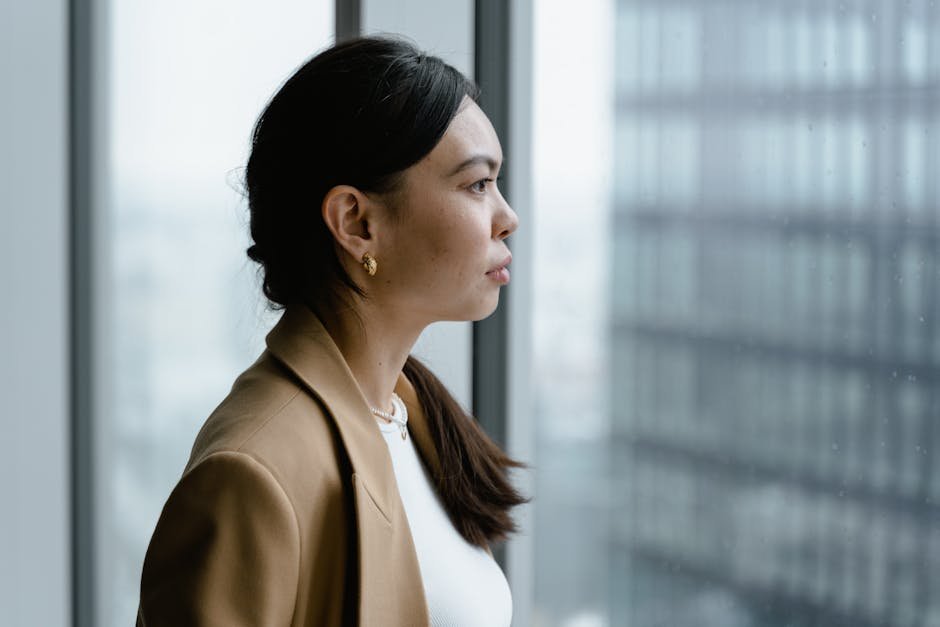 Profile of an Asian woman in a business setting looking thoughtfully out of a window.