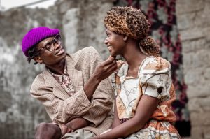 Smiling couple in traditional African dress sharing a joyful moment outdoors. Capturing love and fashion.