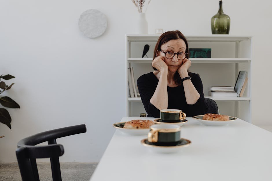 Elderly woman feeling lonely and contemplative at a dining table with coffee and pastries.