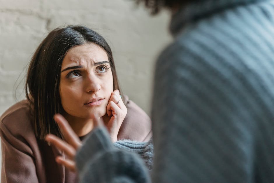 Woman listening thoughtfully during a serious conversation indoors.