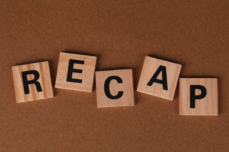 Wooden Scrabble tiles spelling 'RECAP' on a brown textured background. Text concept image.
