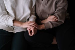 Two individuals sitting together, providing comfort and support with gentle touch.