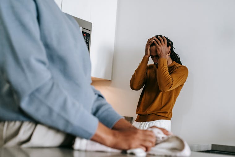 Black man and faceless woman arguing while standing in kitchen and wearing casual clothes in daytime