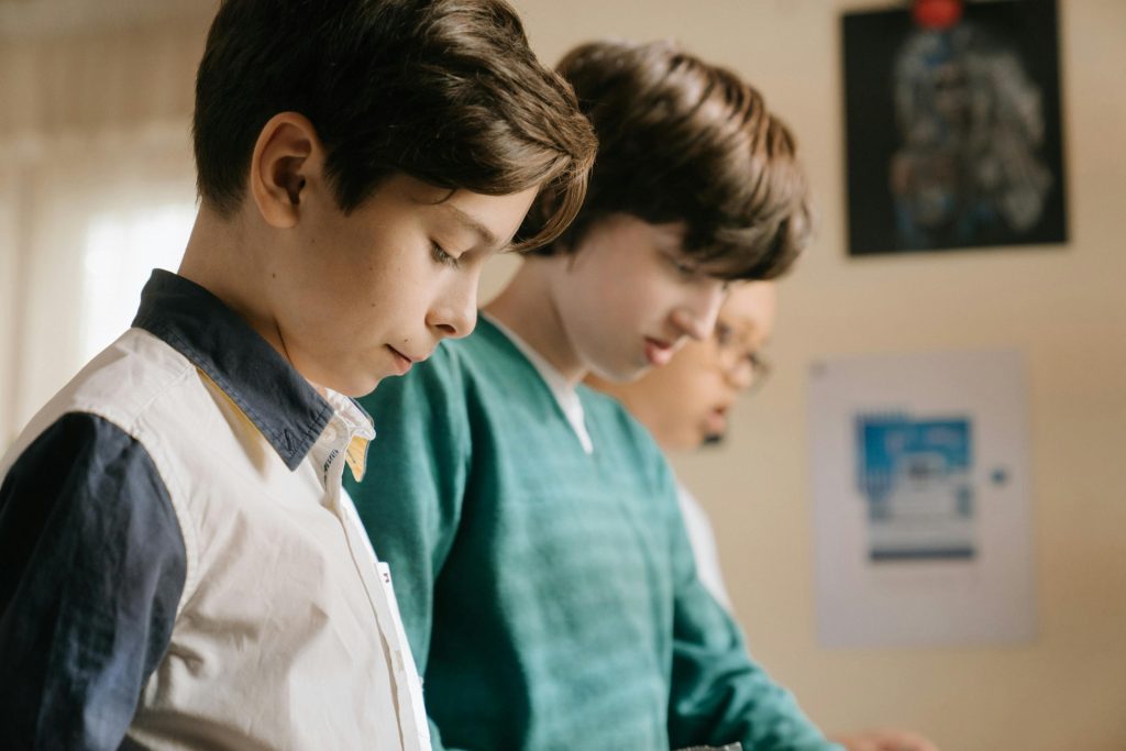 Group of boys concentrating on an educational project indoors, highlighting learning and friendship.
