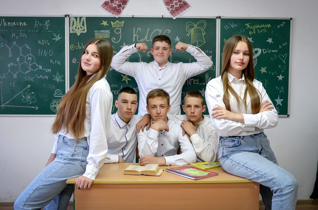 Teen students posing confidently in a classroom with educational chalkboard background.